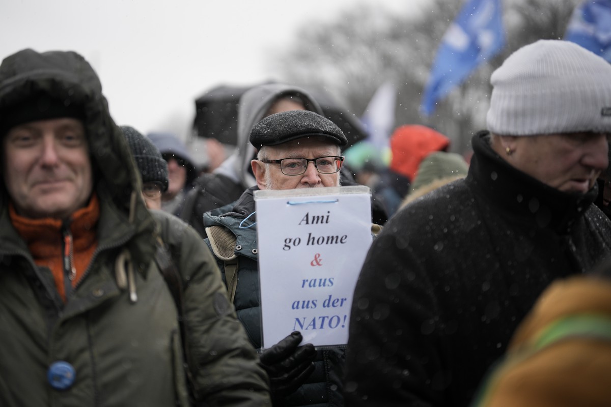 A man holds a poster reading 'Ami Go Home and Out of the NATO!' During a demonstration supporting a so called 'Manifesto for Peace' in Berlin, Saturday, Germany,Feb. 25, 2023. The  ...