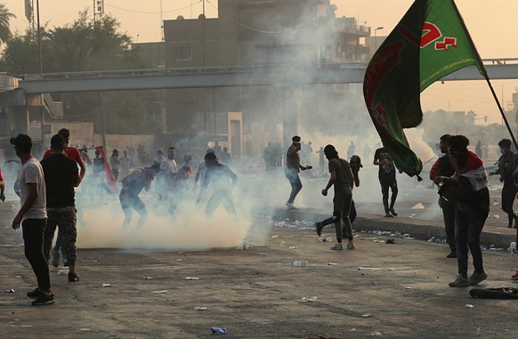Protesters react to tear gas fired by Iraqi security forces during a demonstration in Baghdad, Iraq, Wednesday, Oct. 2, 2019. Iraqi officials said several protesters have been killed Wednesday and sco ...