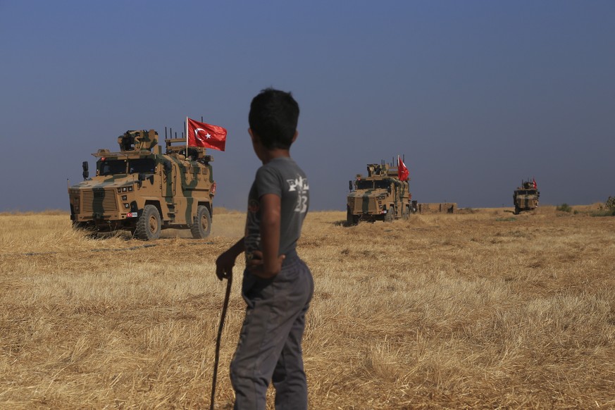 A Turkish n armored vehicles patrol as they conduct a joint ground patrol with American forces in the so-called &quot;safe zone&quot; on the Syrian side of the border with Turkey, near the town of Tal ...