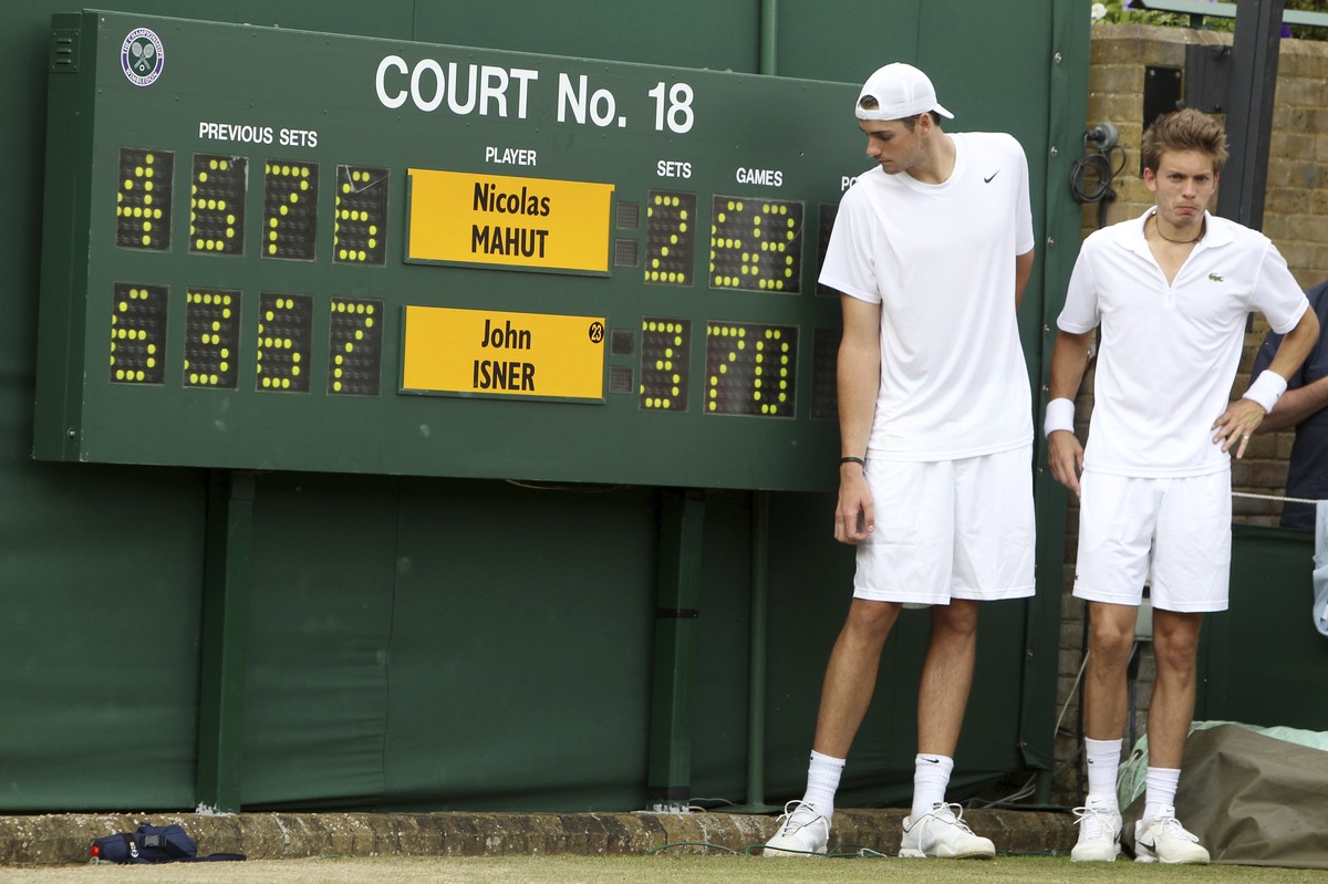 FILE - In this June 24, 2010, file photo, John Isner of the United States, left, and France's Nicolas Mahut pose for a photo next to the scoreboard following their epic men's singles match a ...