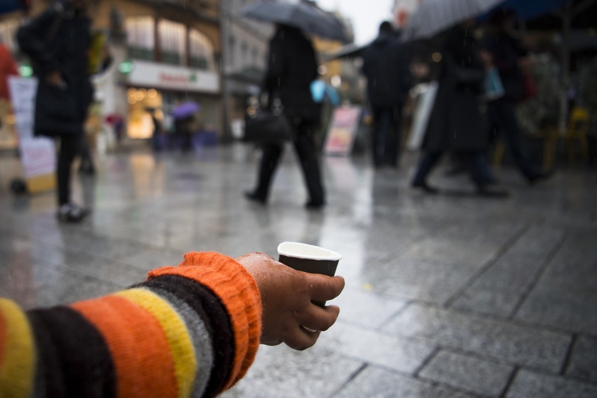 Une mendiante demande de l'argent aux passants alors que des militants du parti Solidarites Vaud recoltent des signatures dans la rue pour lancer le referendum contre l'interdiction de la me ...