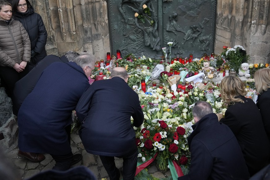 The Chancellor of Germany Olaf Scholz, center left, places flowers outside St. John&#039;s Church near a Christmas Market, where a car drove into a crowd on Friday evening, in Magdeburg, Germany, Satu ...