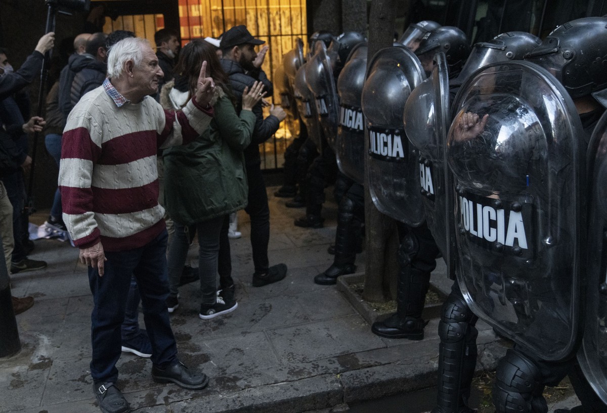 A supporter of Cristina Fernandez, Argentina's former president and the country's current vice president, gestures to riot policemen during a protest in Buenos Aires, Argentina, Saturday, Au ...