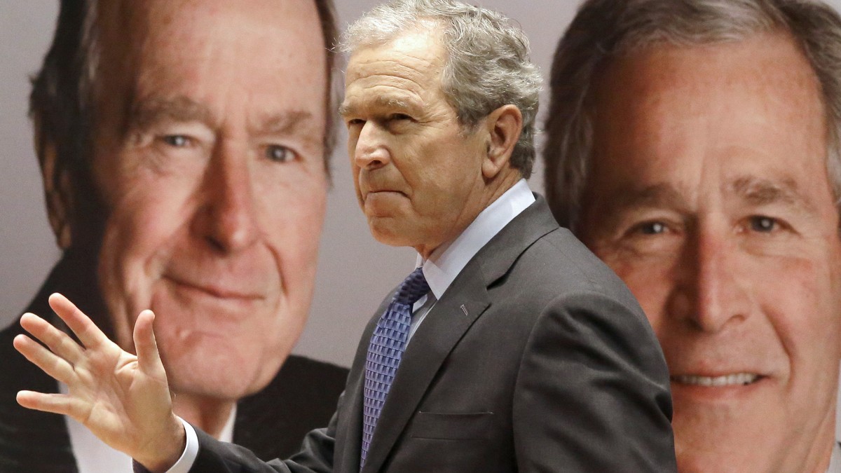 Former President George W. Bush passes by a portrait of himself and his father former President George H.W. Bush as he takes the stage to discuss his new book, "41: A Portrait of My Father"  ...