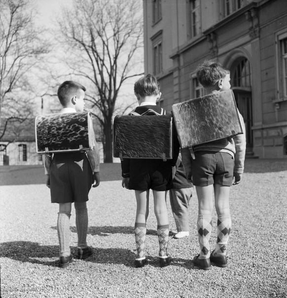 Der erste Schultag in Ostermundigen bei Bern, aufgenommen im Jahr 1958. Drei Knaben mit ihren neuen Scvhultornistern schreiten auf das Schulhaus zu. Siehe dazu den originalen vierseitigen Bildbericht  ...