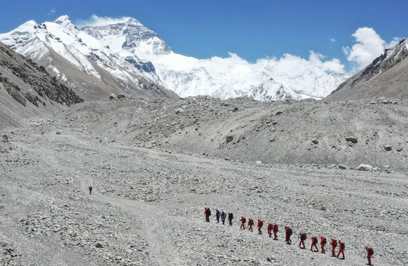 FILE - In this May 16, 2020, file photo released by Xinhua News Agency, Chinese surveyors hike toward a higher spot from the base camp on Mount Qomolangma at an altitude of 5,200 meters. China has ope ...