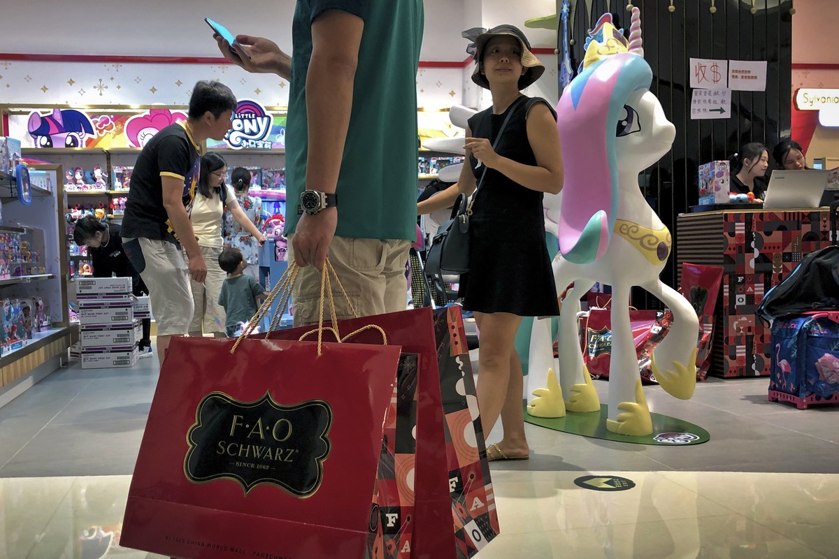 FILE - In this June 1, 2019, photo, file a man carries a paper bags containing toys purchased from the FAO Schwarz as people shop at the newly open FAO Schwarz toy store at the capital city's pop ...