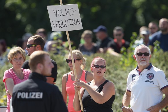 HEIDENAU, GERMANY - AUGUST 26: An onlooker holds a sign that reads: &quot;Nation Traitor&quot; during a visit by German Chancellor Angela Merkel at the nearby aslyum shelter that was the focus of rece ...