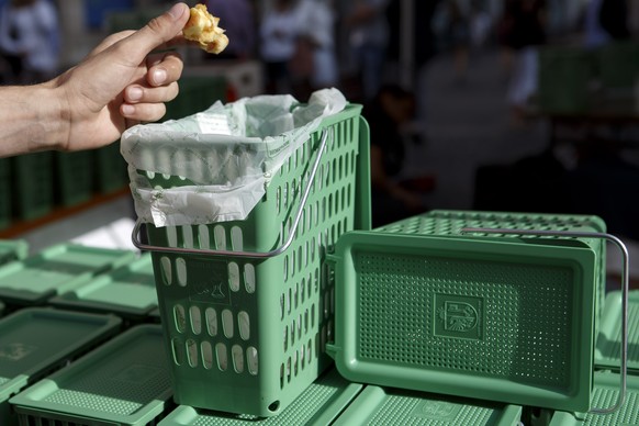 Une personne jette le reste d&#039;une pomme dans une poubelle verte, lors du lancement de la distribution de 100&#039;000 &quot;P&#039;tites poubelles vertes&quot; pour la recuperation des dechets de ...