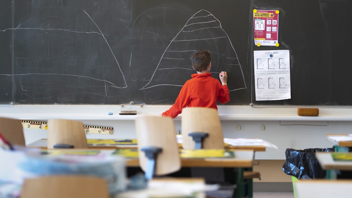 A child draws on the blackboard in an almost empty classroom as he attends a school childcare service at the school "Etablissement primaire Pestalozzi " during the state of emergency of the  ...