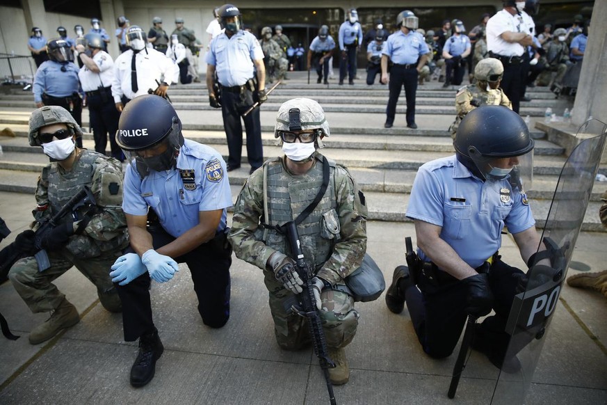 Philadelphia police and Pennsylvania National Guard take a knee at the suggestion of Philadelphia Police Deputy Commissioner Melvin Singleton, unseen, outside Philadelphia Police headquarters in Phila ...