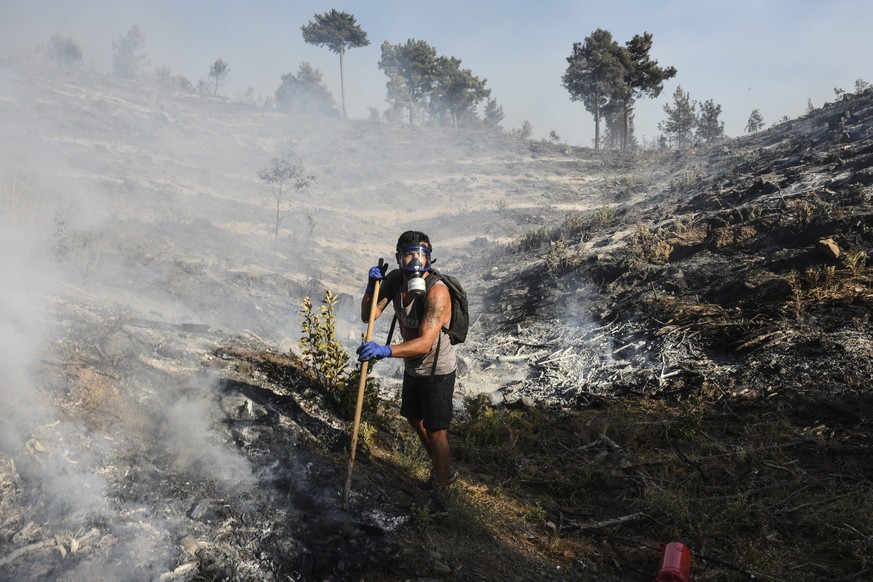 A man wearing a gas mask clears debris in a burnt out forest in Semir village, near Manavgat, Antalya, Turkey, Tuesday, Aug. 3, 2021. Turkish President Recep Tayyip Erdogan���s government is facing in ...