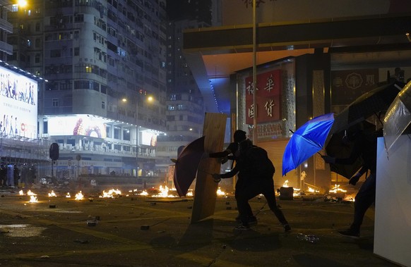 Protestors react as police fire tear gas in the Kowloon area of Hong Kong, Monday, Nov. 18, 2019. As night fell in Hong Kong, police tightened a siege Monday at a university campus as hundreds of anti ...