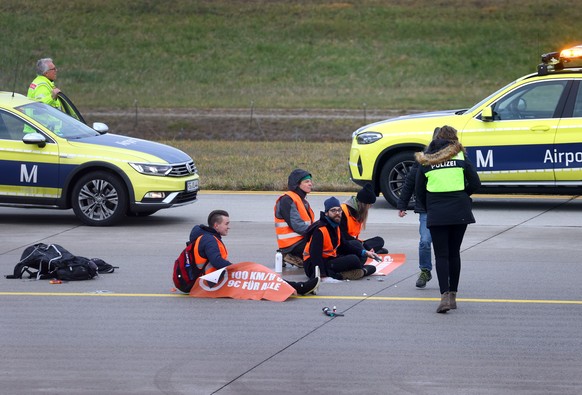 08.12.2022, Bayern, M�nchen: Vier Klimaaktivisten sitzen mit angeklebten H�nden auf dem Zubringer einer Start-und Landebahn am Airport Franz-Josef-Strau�. Foto: Karl-Josef Hildenbrand/dpa +++ dpa-Bild ...