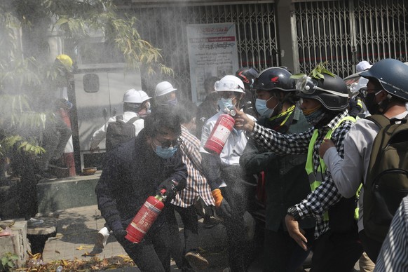 Anti-coup protesters discharge fire extinguishers to counter the impact of the tear gas fired by police during a demonstration in Mandalay, Myanmar, Sunday, March 7, 2021. The escalation of violence i ...