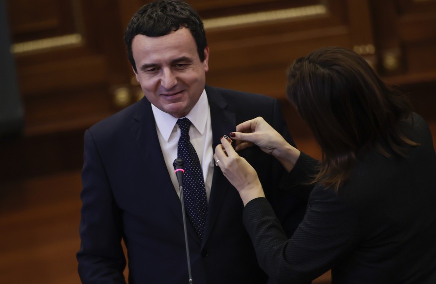 epa08190845 Ganimete Musliu (R), opposition lawmaker, places a national Albanian and Kosovo flag pin on Albin Kurti, the leader of the Self-determination (Vetevendosje) party, during the parliamentary ...