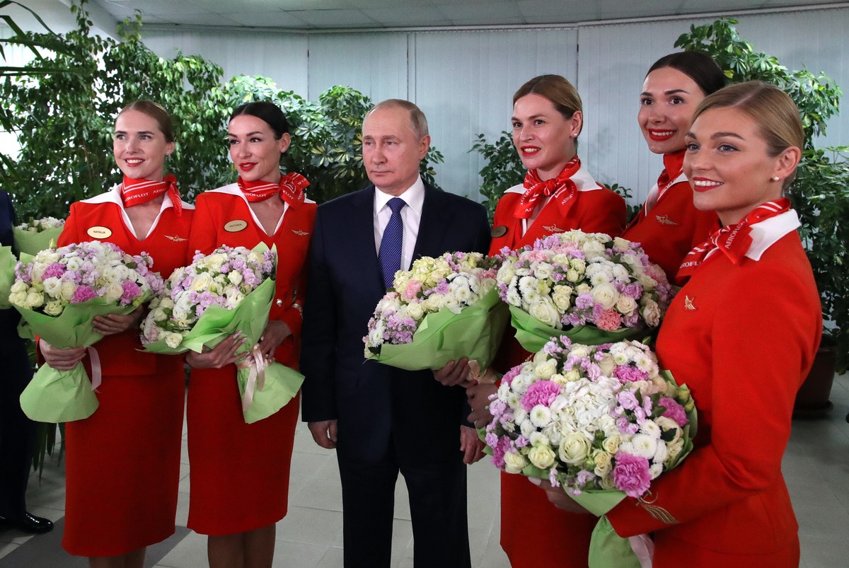 epa09803745 Russian President Vladimir Putin (R) poses for pictures with women flight crew of Russian airlines during his visit to the aviation training center of PJSC Aeroflot on the eve of Internati ...