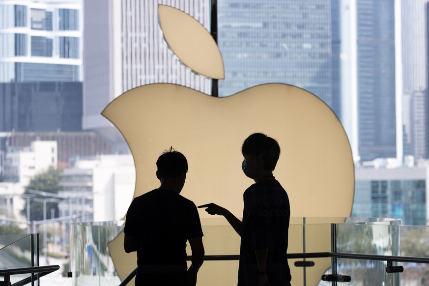 epa09825850 Apple Store staff talk in front of the Apple Inc. logo at the company