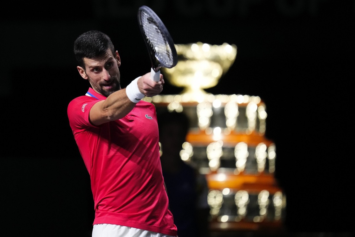 Serbia's Novak Djokovic reacts, with the Davis Cup on the background, during a Davis Cup quarter-final tennis match against Britain's Cameron Norrie in Malaga, Spain, Thursday, Nov. 23, 2023 ...