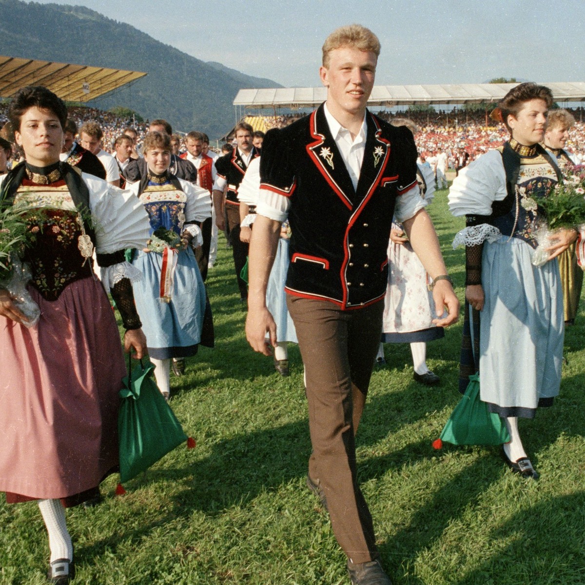 Der neue Schwingerkoenig Adrian Kaeser schreitet am 21. August 1989 in Stans beim Eidgenoessischen Schwing- und Aelplerfest, umgeben von Trachtenfrauen, zur Siegerehrung. (KEYSTONE/Martin Ruetschi)