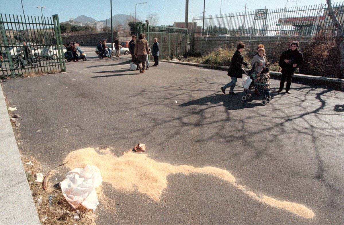 Bystanders look at the place in front of a supermarket in Naples' suburbs, where 14-y-old Giovanni Gargiulo was shot to death by mobsters in broad daylight at 0830, Wednesday February 18, 1998. A ...