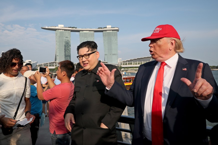 epa06792907 US President Donald Trump impersonator Dennis (R) gestures next to North Korean leader Kim Jong-un impersonator Howard (C-L) pictured against the Marina Bay Sands hotel as they pose for ph ...