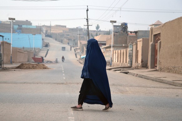 epa11927501 A burqa-clad Afghan woman walks on a road in Kandahar, Afghanistan, 27 February 2025. Afghanistan marks the fifth anniversary of the agreement between the United States and the Taliban, si ...