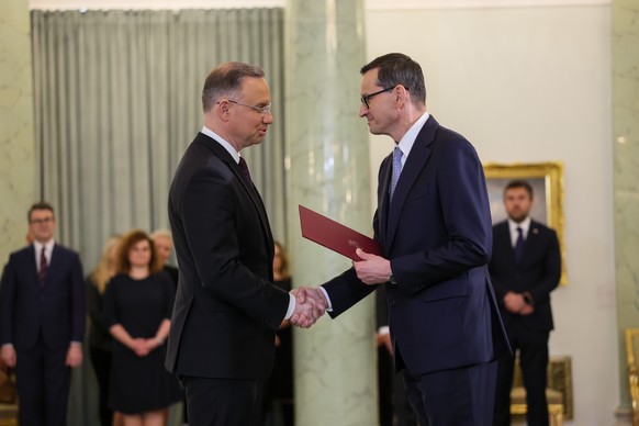 epa10973812 Polish President Andrzej Duda (L) shakes hands with Prime Minister Mateusz Morawiecki (R) during a ceremony for the appointment of the Prime Minister at the Presidential Palace in Warsaw, ...