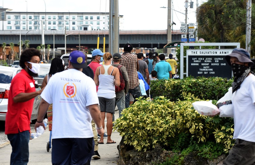 People wait in line to receive a free Thanksgiving meal at the Salvation Army on November 26, 2020 in Orlando, Florida. Takeout meals were served this year due to the ongoing COVID-19 pandemic. (Photo ...