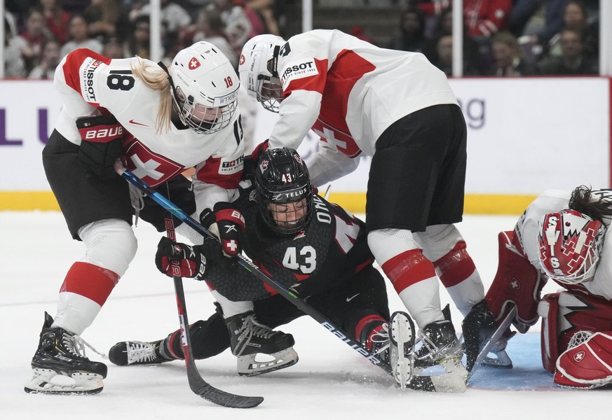 Canada forward Kristin O&#039;Neill (43) is knocked down by Switzerland&#039;s Stefanie Wetli (18) and Shannon Sigrist (9) during the third period of a game at the women?s world hockey championships W ...
