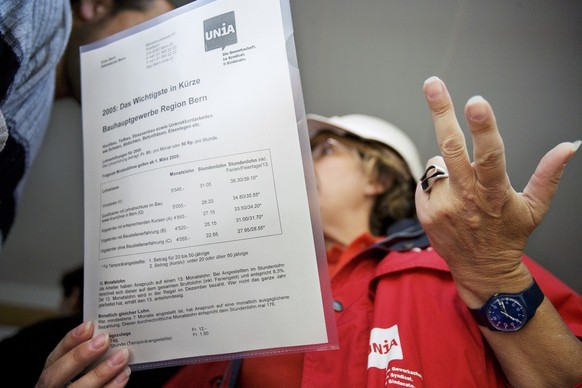 Eine Vertreterin der Gewerkschaft UNIA begleitet einen Kontrolleur am 17. August 2005 auf einer Baustelle in Bern bei der Pruefung von Arbeitsbewilligungen der Arbeiter auf einer Baustelle. Damit soll ...