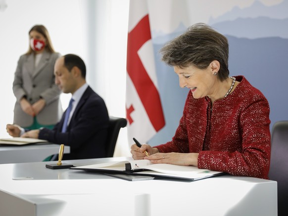 epa09530060 Swiss Federal Councillor Simonetta Sommaruga, right, and Levan Davitashvili, Georgian minister of Environmental Protection and Agriculture, sign a climate agreement during an official visi ...