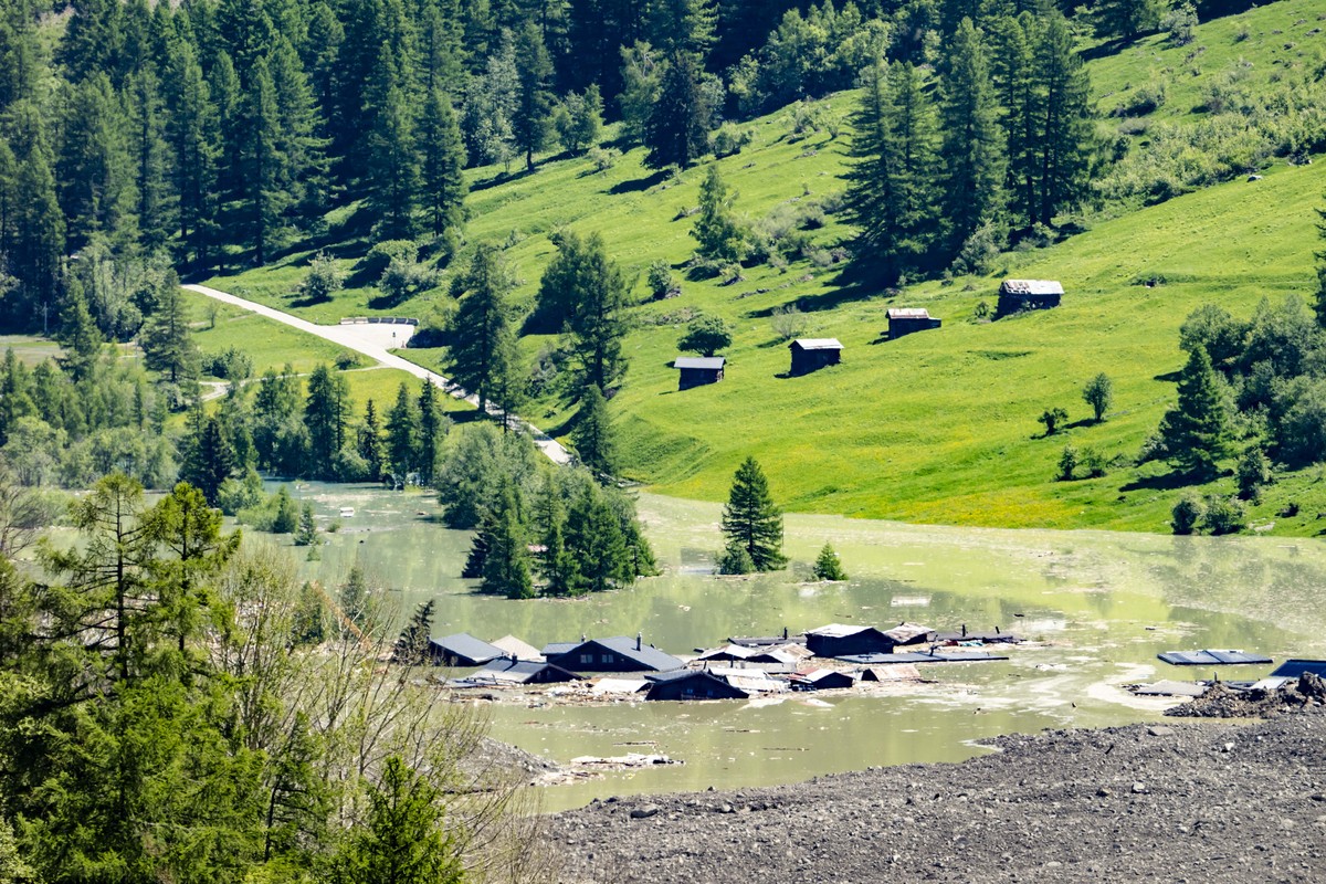 epa12144821 Water from the Lonza river flows over the mud and stone, after the formation of a lake on the last houses of the village of Blatten, Switzerland, 30 May 2025. A large part of the Blatten v ...