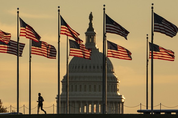 epaselect epa10293806 A jogger passes US flags on the National Mall in front of the Capitol Building in Washington, DC, USA, 08 October 2022. The US midterm elections are held every four years at the  ...