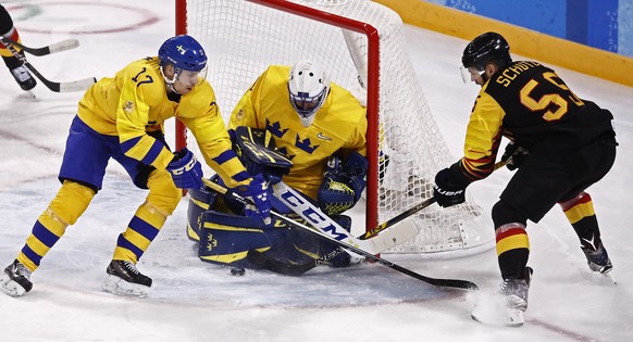 epa06532568 Goalie Jhonas Enroth (C) and Par Lindholm (L) of Sweden blocks a shot against Felix Schutz (R) of Germany during their preliminary round match inside the Kwandong Hockey Centre at the Pyeo ...