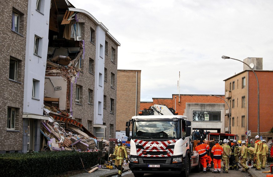 Rescue workers look up at rubble scattered in front of a building after a blast occurred in Turnhout, Belgium, Friday, Dec. 31, 2021. Rescue services said it was still unclear what caused the blast or ...