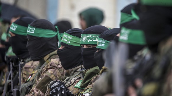 epa11915750 Armed fighters from Hamas&#039; Izz ad-Din al-Qassam Brigades stand guard during the handover of three Israeli hostages to Red Cross representatives in Al Nuseirat refugee camp, central Ga ...