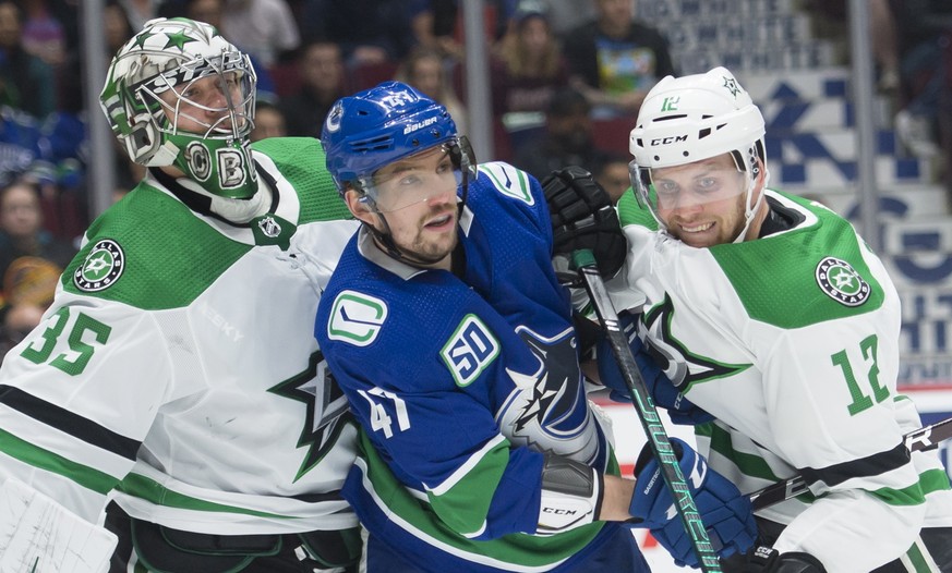 Dallas Stars center Radek Faksa (12) tries to clear Vancouver Canucks Sven Baertschi from in front of Stars goaltender Anton Khudobin (35) during the first period of an NHL hockey game Thursday, Nov.  ...