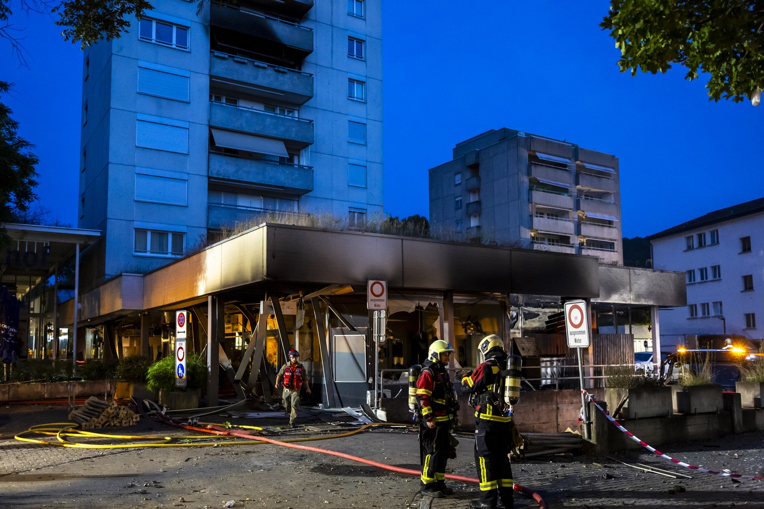 Einsatzkraefte der Feuerwehr beim Markthof Nussbaumen nach einer Explosion einer Tiefgarage und einem anschliessenden Brand in einem Hochhaus am Donnerstag, 13. Juni 2024 in Nussbaumen. Bei einer Expl ...