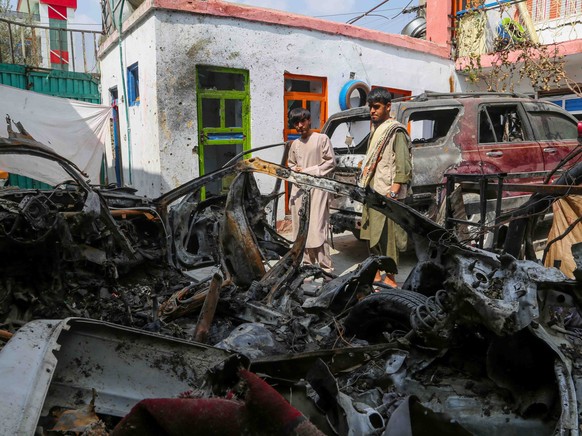 epa09476246 Family members of the victims of a US drone strike, stand beside the wreckage of the damaged vehicles, at their home, a day after US apologised for mistakenly attacking the civilians, in K ...