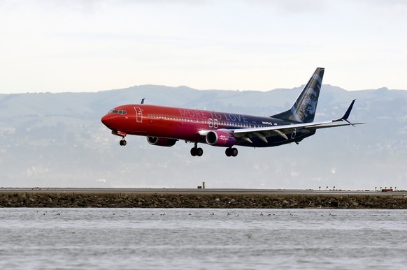A specially painted, co-branded Alaska Airlines and Virgin America 737-900ER aircraft, painted in shimmering red, purple and blue and featuring the slogan âMore to love,â lands at San Francisco In ...