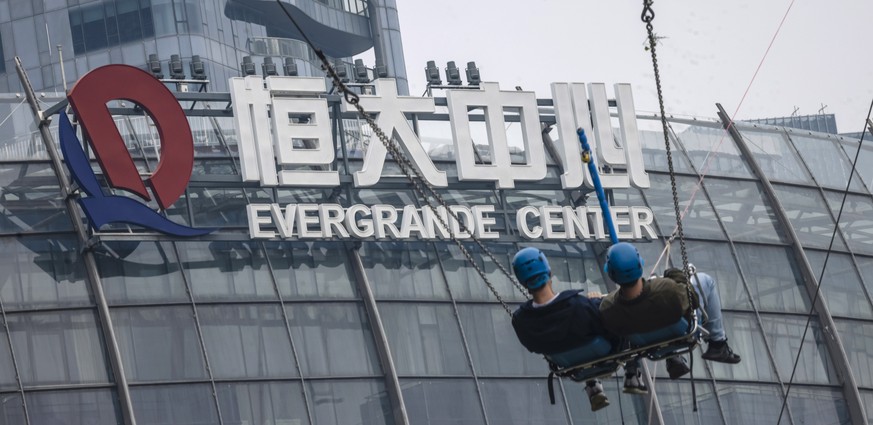 epaselect epa09538453 People ride on a swing in the amusement park in front of the Evergrande Center building in Shanghai, China, 22 October 2021. According to the state-owned media, China Evergrande  ...