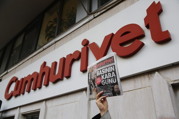 epa05044744 A Turkish man holds the Cumhuriyet newspaper as others gather in protest in front Turkish newspaper Cumhuriyet publishing house, in support of Can Dundar and Erdem Gul who were arrested by ...