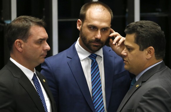 Senate President Davi Alcolumbre, right, talks with lawmaker Eduardo Bolsonaro, center, and Senator Flavio Bolsonaro, the son of the nation's president, during the final voting session on pension ...