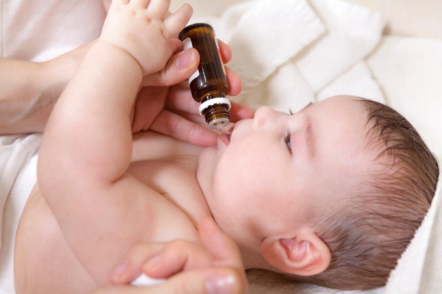 Ein Arzt gibt dem Neugeborenen Vitamin D3. Kinderimpfung mit Tropfen in einer Klinik