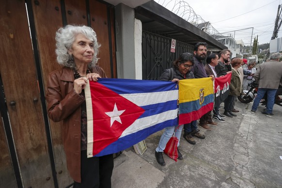 epa12795795 People hold Ecuadorian and Cuban flags during a demonstration outside the Cuban Embassy in Quito, Ecuador, 04 March 2026. The government of Ecuador declared Cuban Ambassador Basilio Gutier ...