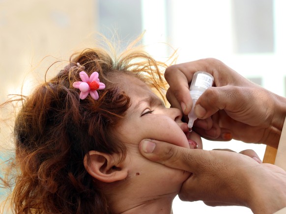 epa10091363 A health worker gives polio vaccine drops to a child during a three-day door to door vaccination drive in Kandahar, Afghanistan, 25 July 2022. According to UNICEF, repeated immunizations h ...