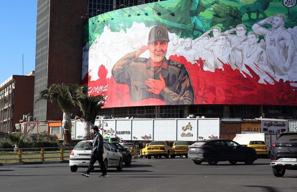 epa12617714 Iranians walk past a huge banner of former Iran Islamic Revolutionary Guard Corps (IRGC) Quds Force commander Qasem Soleimani ahead of the sixth anniversary of his assassination at Valiasr ...