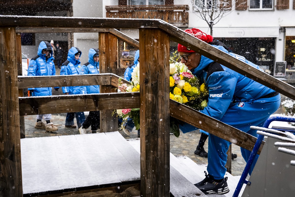 epa12687669 The Italian women ski team with Gianluca Rulfi, technical director of Italian women's alpine ski team, pay tribute to the victims in front of the entrance of the 'Le Constellatio ...