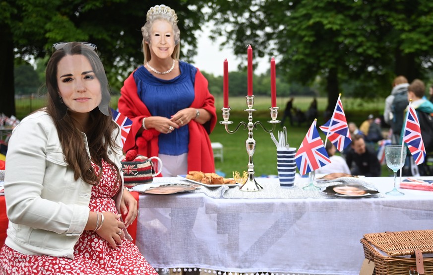 epa09997097 People wearing face masks of the British Queen and the Duchess of Cambridge enjoy a picnic as they take part in The Big Lunch on the Long Walk during the celebrations of the Platinum Jubil ...